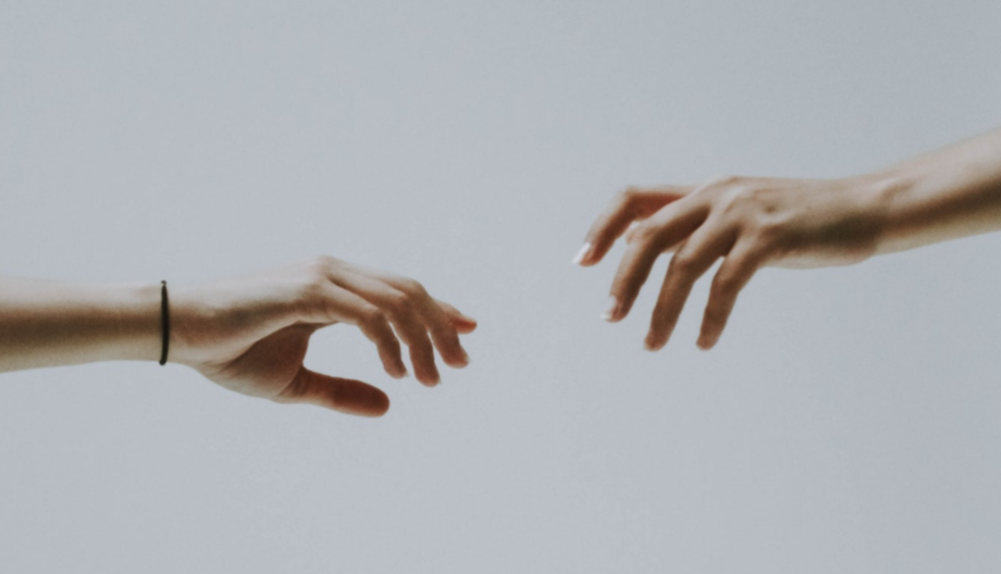 two hands reaching to each other to illustrate transitioning from online dating to offline dating