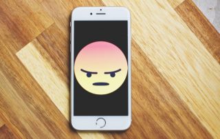 angry face emoji on phone to illustrate dating app algorithms