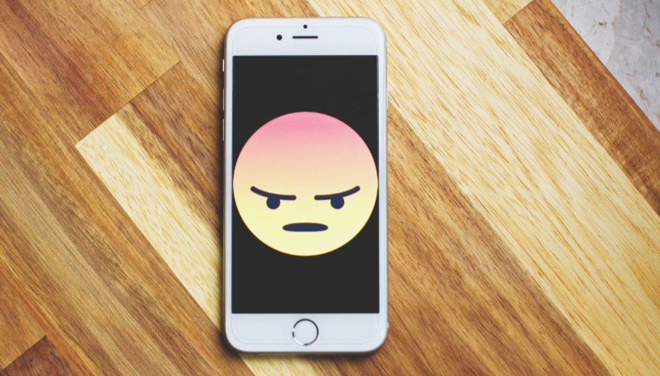 angry face emoji on phone to illustrate dating app algorithms