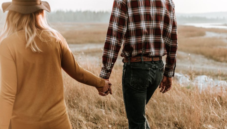 couple holding hands in a field to illustrate rural dating in the us