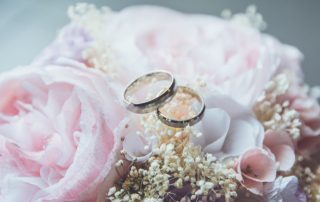 wedding rings on top of a bouquet to illustrate corona weddings