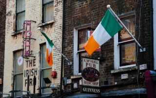 Exterior view of an Irish pub in Dublin with flags and vibrant signage.