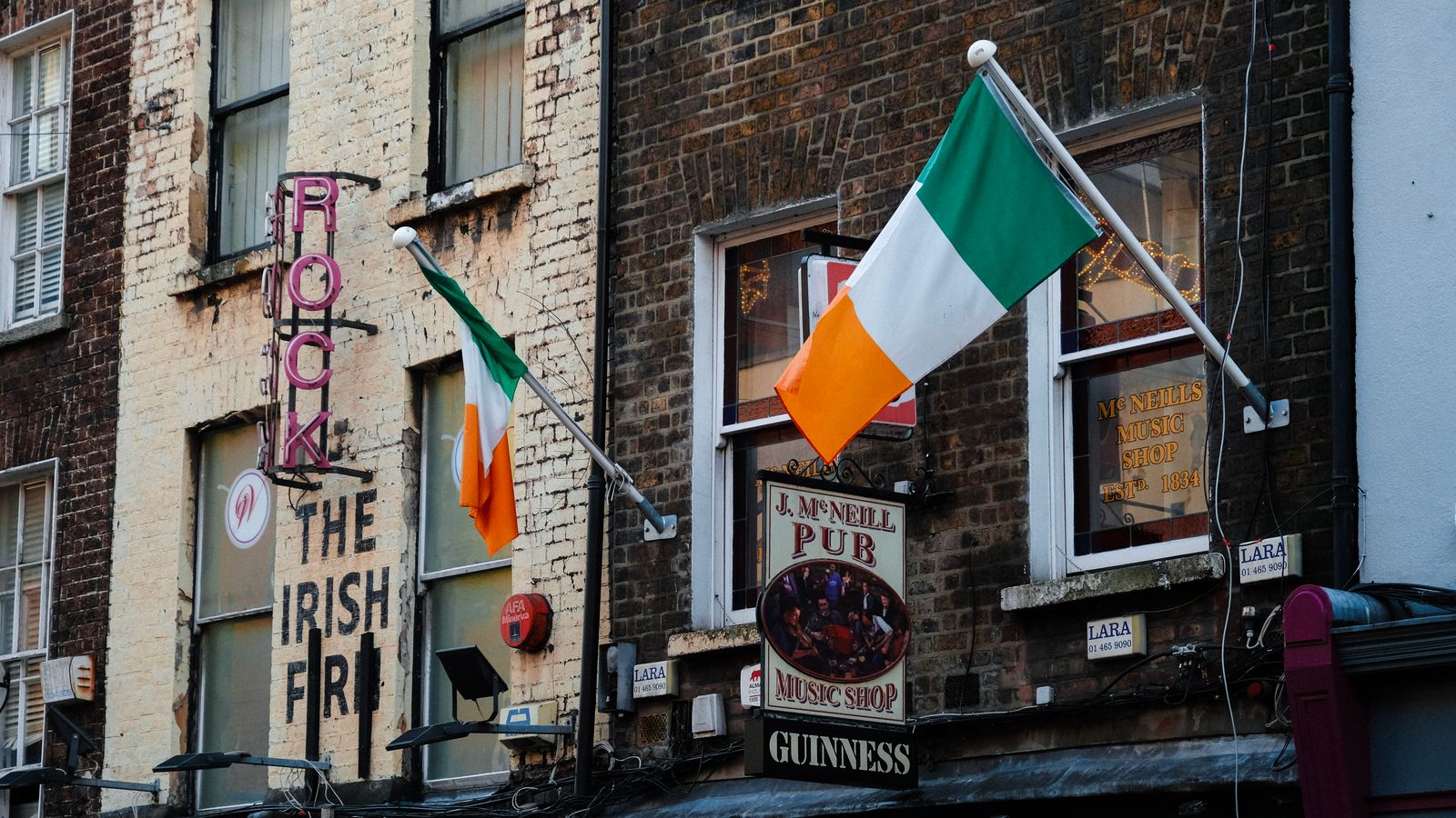 Exterior view of an Irish pub in Dublin with flags and vibrant signage.
