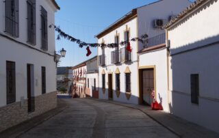 Empty urban street in Spain adorned with festive holiday garlands and red stockings.