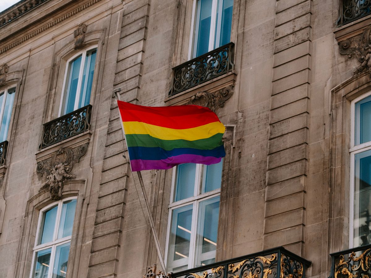 LGBT rainbow pride flag waving in front of a historic building
