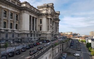 View of Brussels' iconic Palais de Justice with parked cars and urban landscape.