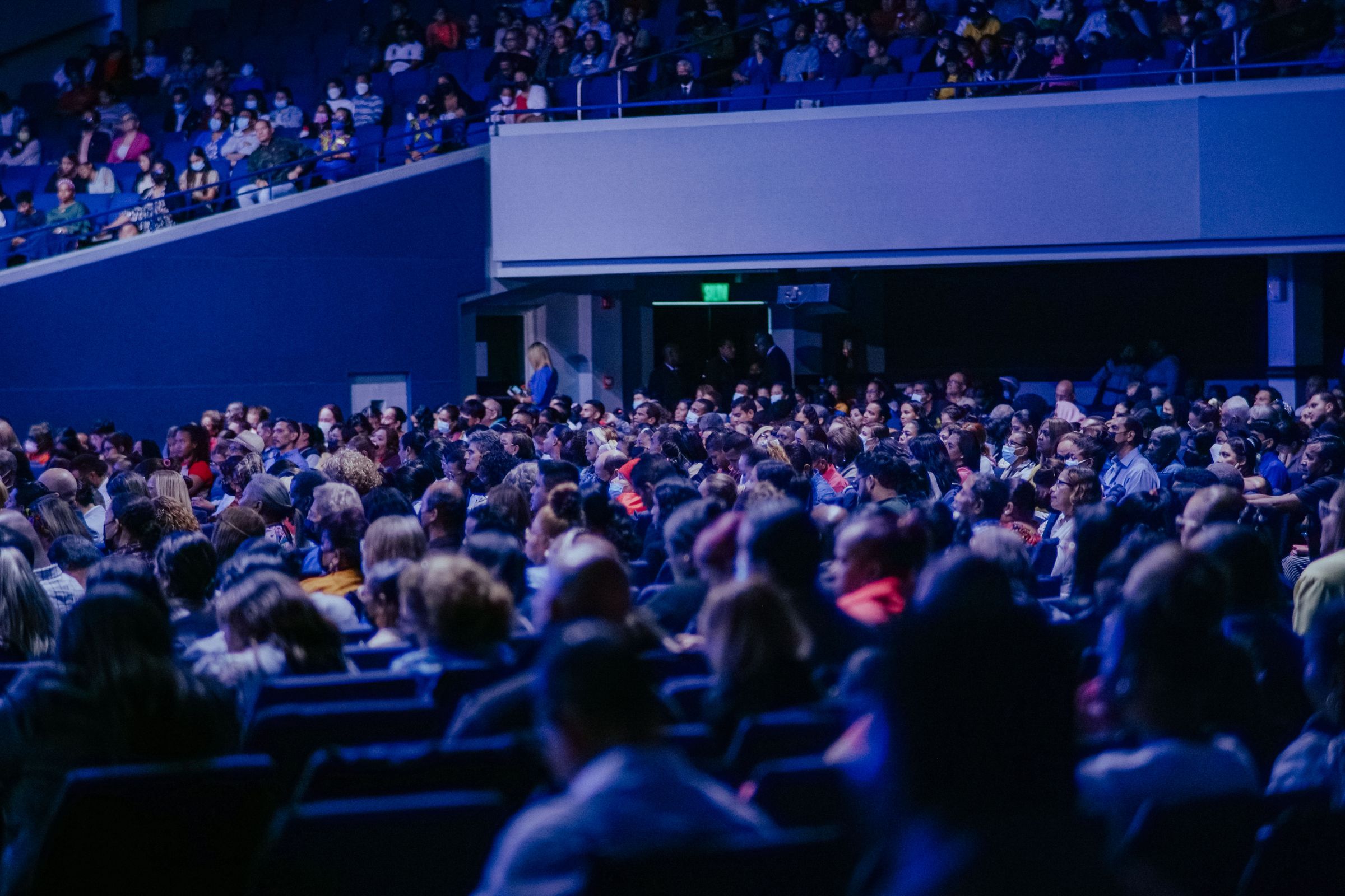 Large audience filling a conference hall to listen to a speaker on stage