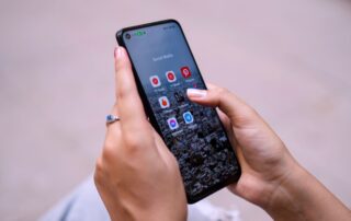 Close-up of hands holding a smartphone displaying social media apps, emphasizing digital connectivity.