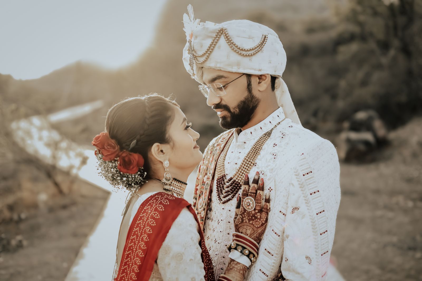 Beautiful Indian couple embraces during an outdoor wedding ceremony, showcasing traditional attire and love.