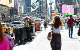 Vibrant urban scene in Times Square with pedestrians and traffic on a sunny day.