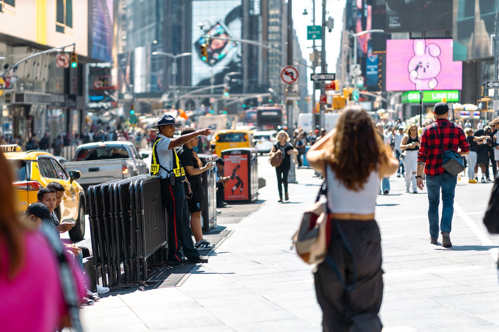 Vibrant urban scene in Times Square with pedestrians and traffic on a sunny day.