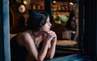 A thoughtful woman in a cozy cafe looks outside, reflecting on a peaceful day.