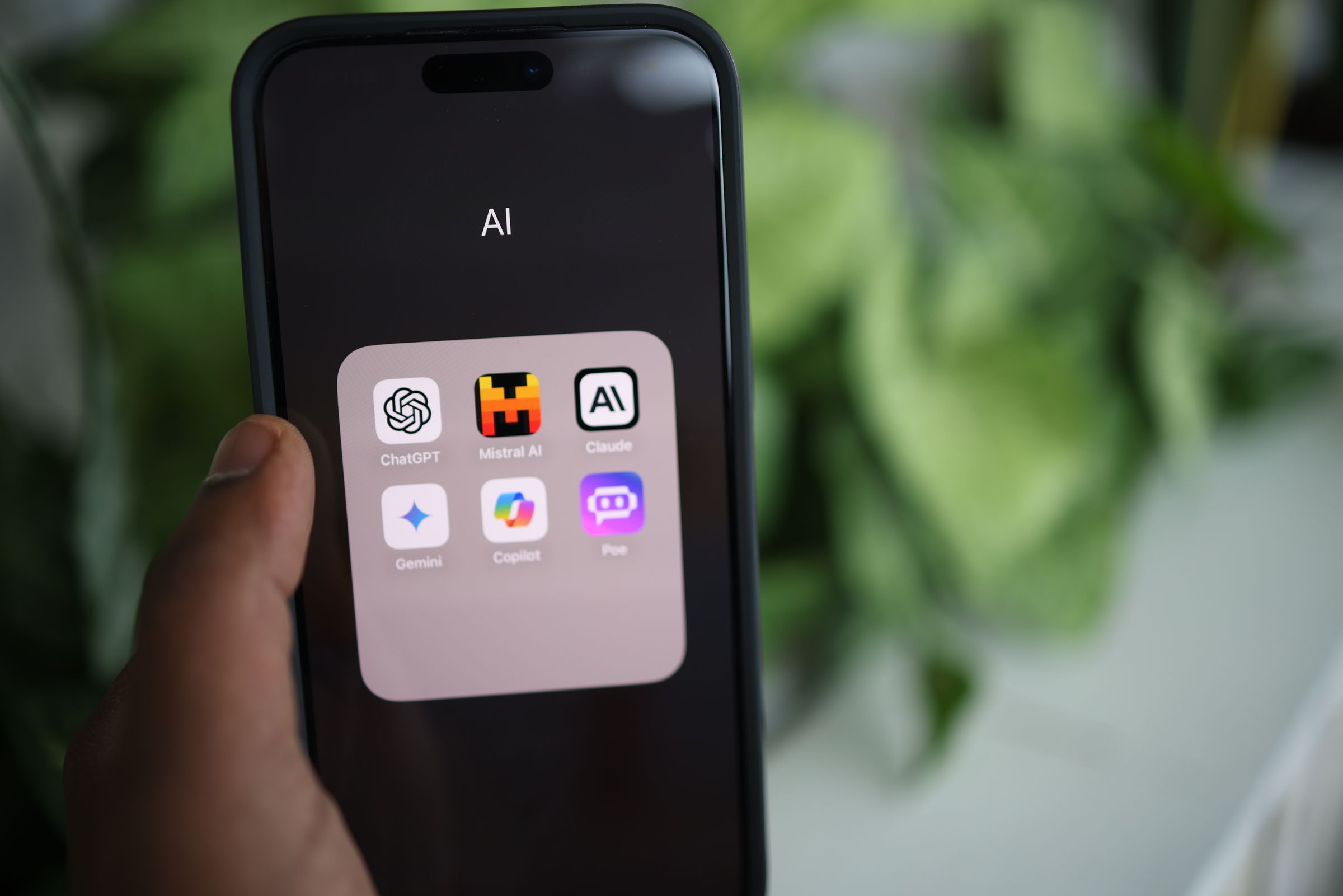 Hand holding a smartphone with AI apps on screen