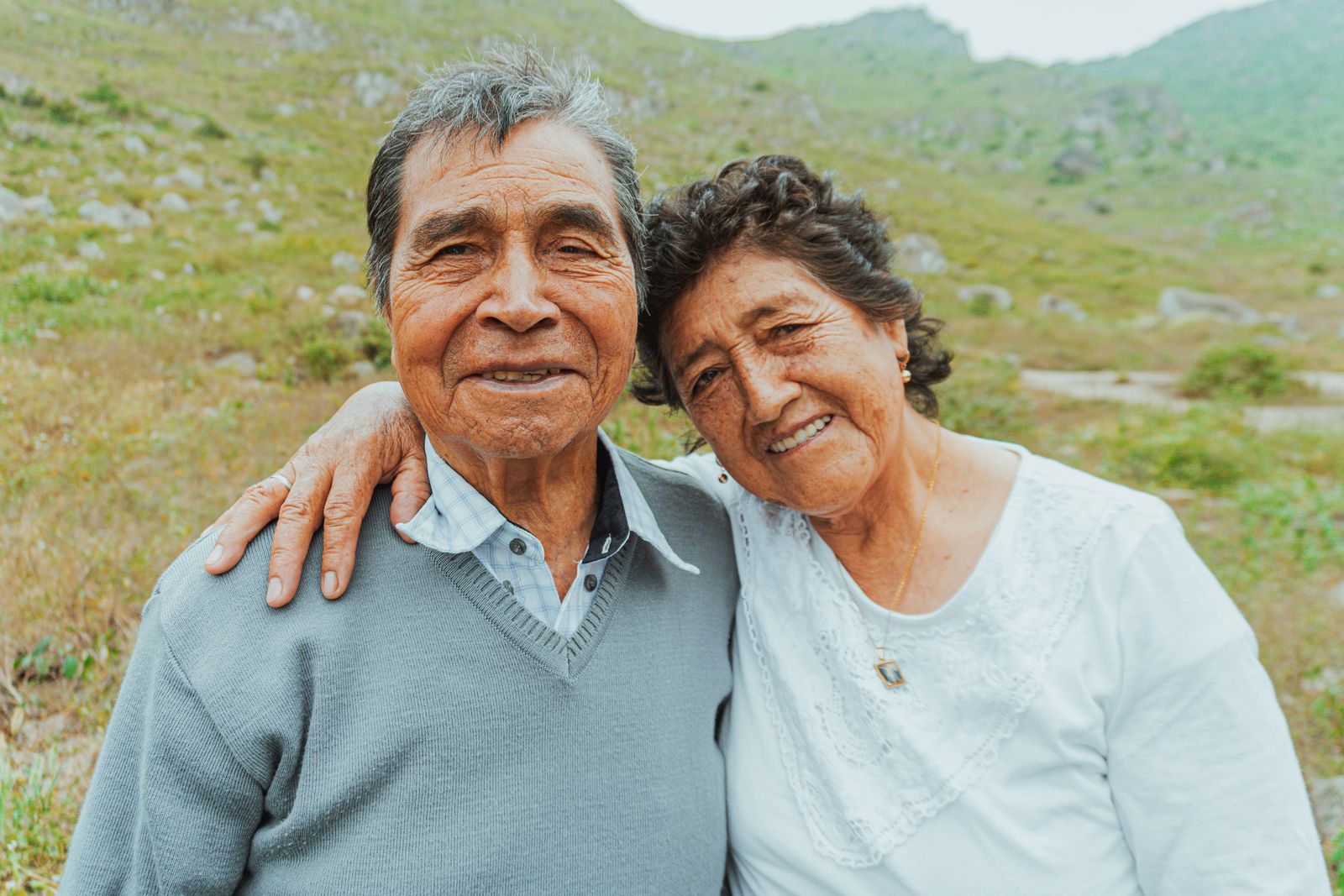 Smiling senior couple embracing in a scenic outdoor setting, expressing love and happiness.