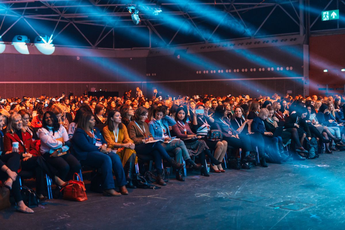 Audience seated in a large auditorium under stage lighting