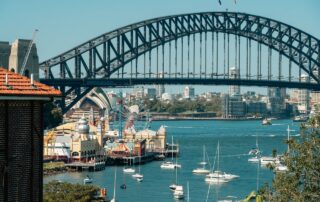 A vibrant view of Sydney Harbour Bridge with Luna Park and sailboats highlighting the iconic skyline.