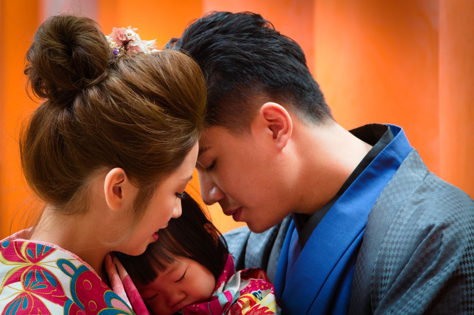A heartfelt moment between parents and child wearing colorful traditional kimonos.