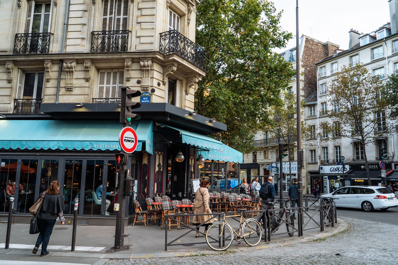 A scenic Paris café on a cobblestone street corner, capturing classic architecture and local life.