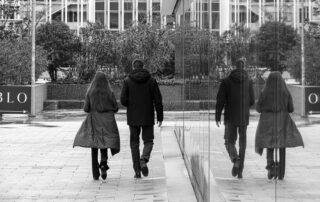 A black and white photo of two people walking by a reflective surface in Madrid.