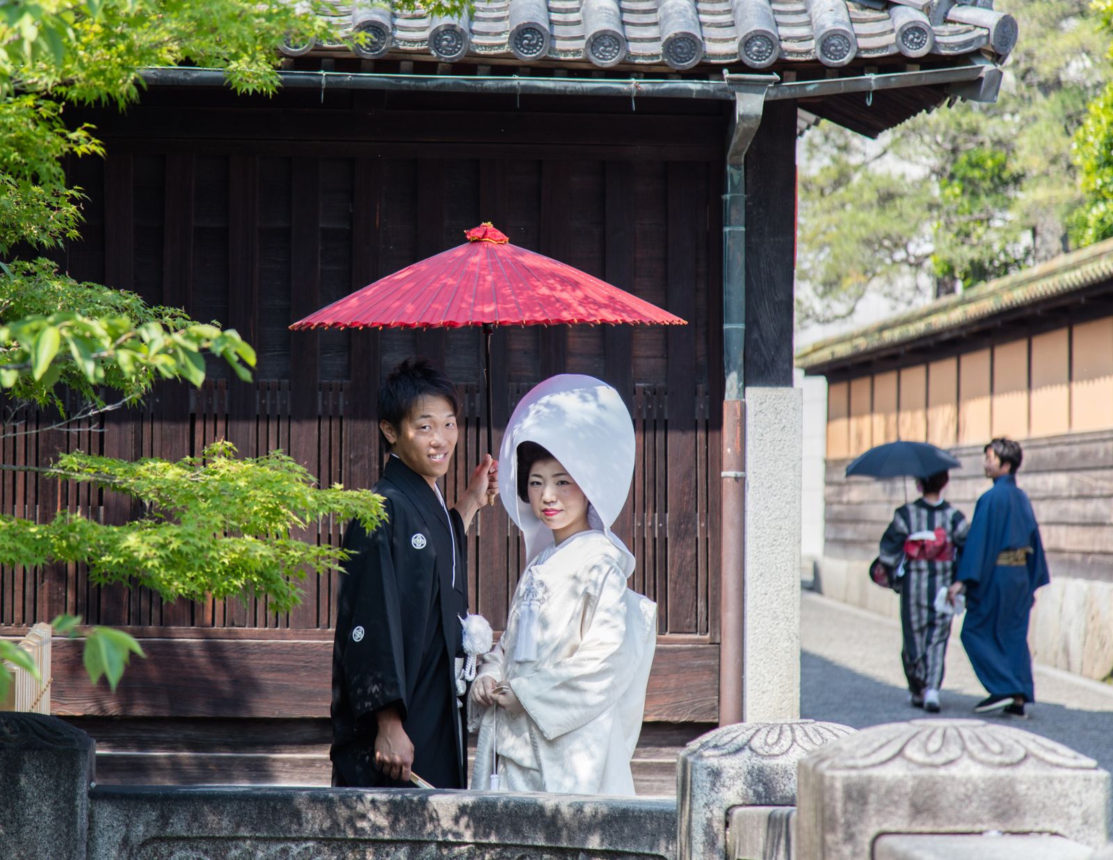 Elegant Japanese wedding couple in traditional attire with parasol in Kurashiki, Japan.
