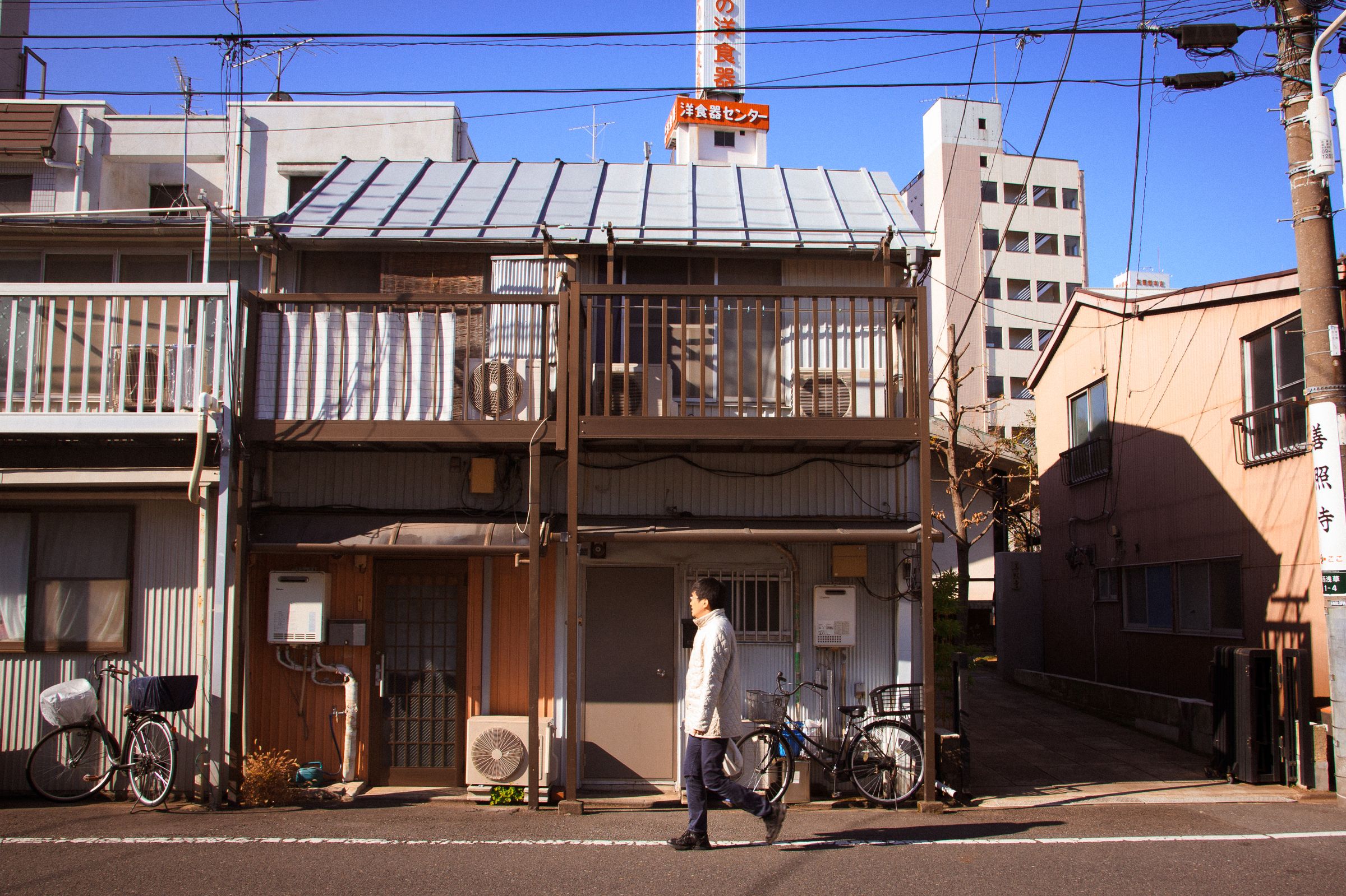 Man walking past a traditional Japanese house