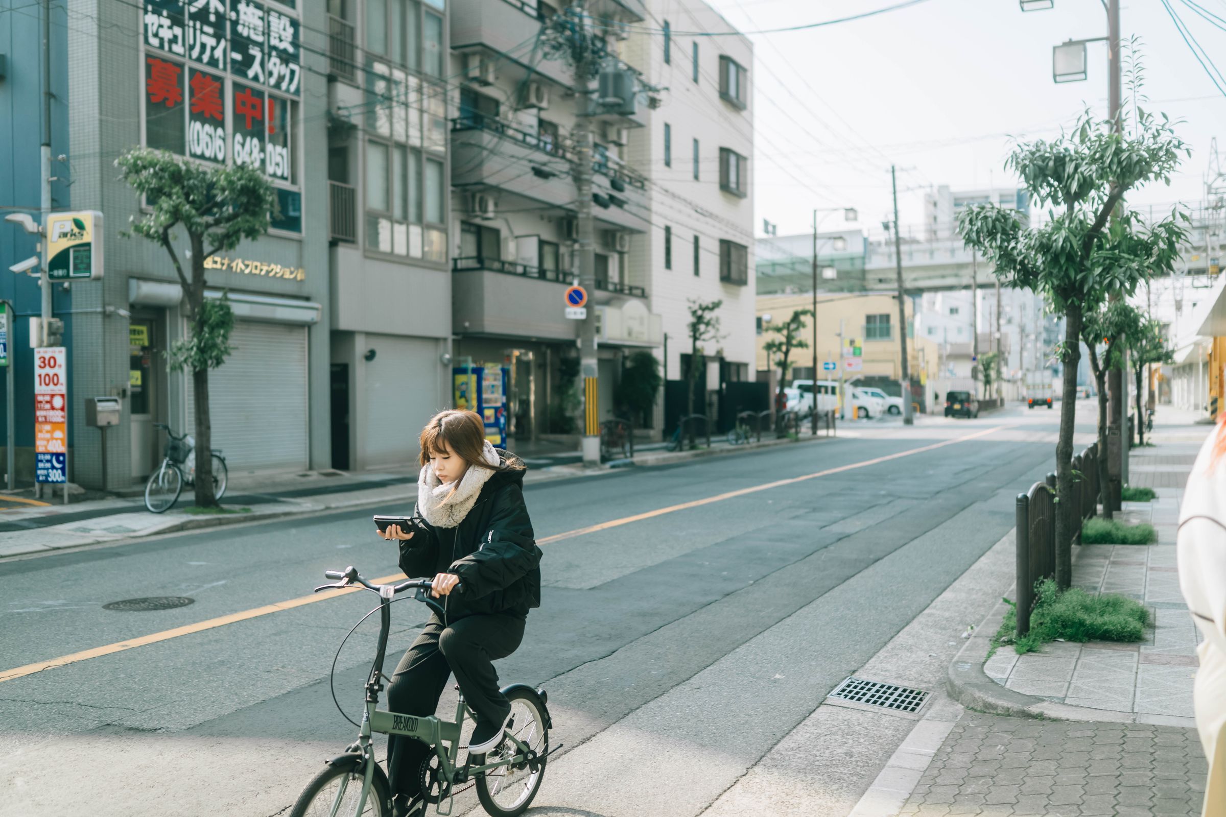 Young woman on her phone cycling a quiet Japanese street