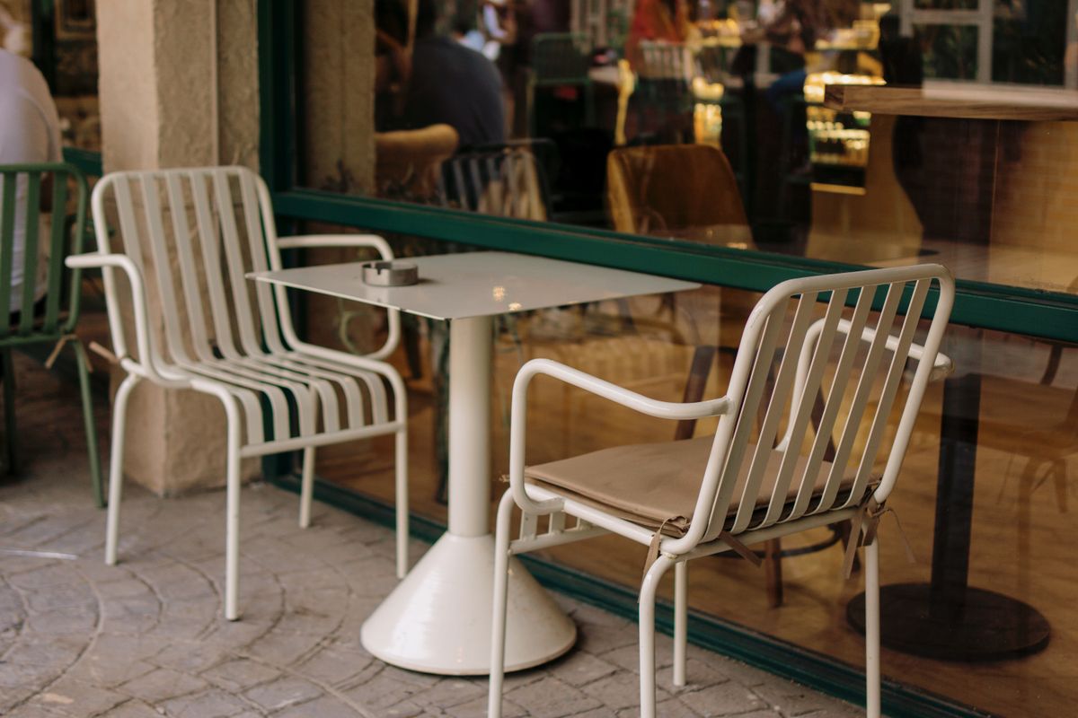 Empty cafe table with two metal chairs outdoors