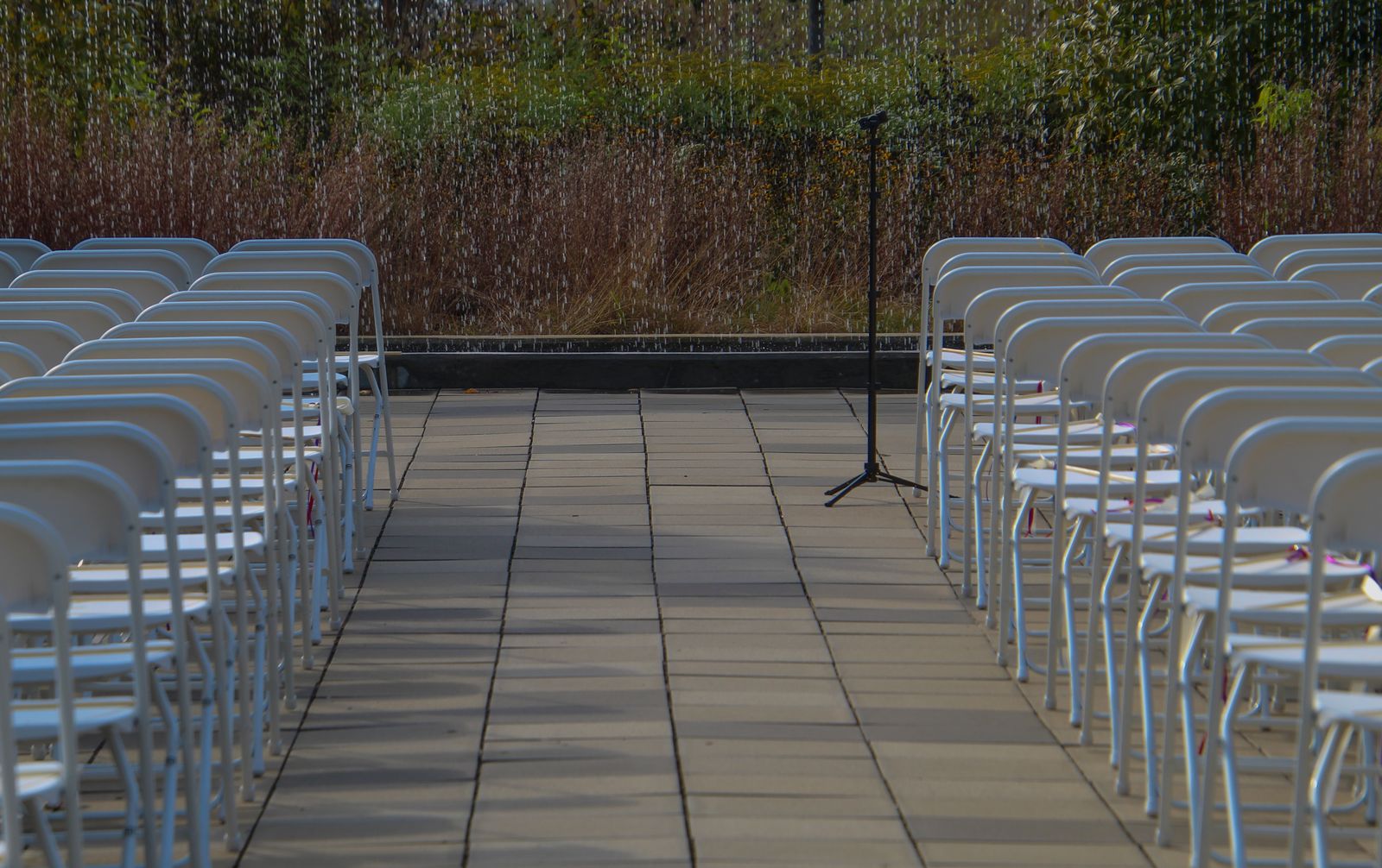 Empty chairs arranged for an outdoor wedding ceremony with a microphone stand.