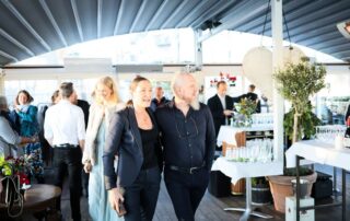 Chic indoor gathering featuring elegantly dressed guests mingling joyfully under a modern roof structure.