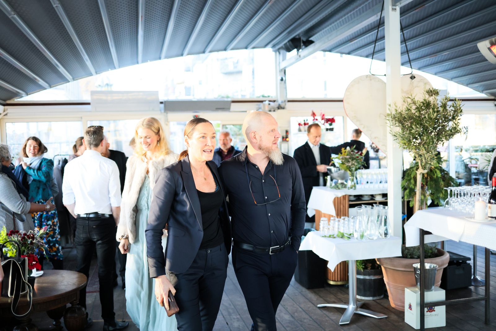 Chic indoor gathering featuring elegantly dressed guests mingling joyfully under a modern roof structure.