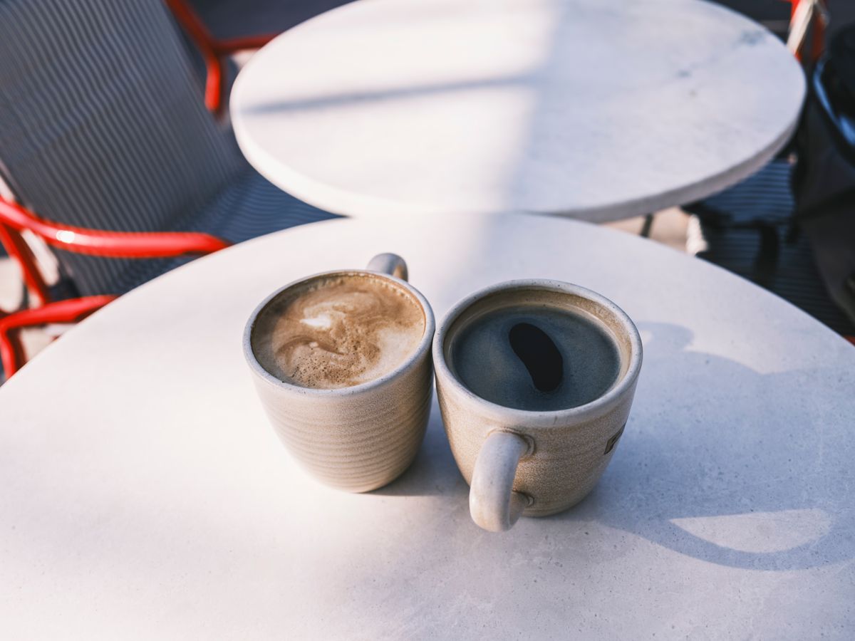 Two cups of coffee on a sunlit cafe table