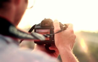 Photographer holding a DSLR camera at sunset