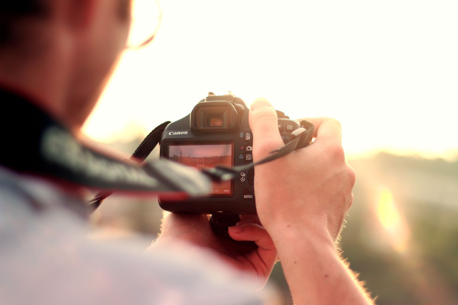 Photographer holding a DSLR camera at sunset