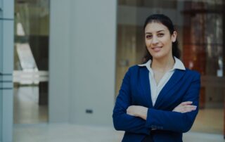 Professional woman in a blue suit smiling confidently in an office setting.