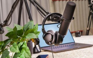 A modern podcast studio setup with a microphone, headphones, and laptop, ideal for media production and online broadcasting.