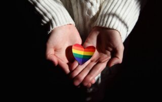 Hands offering a rainbow heart symbolizing love and LGBTQ+ pride.