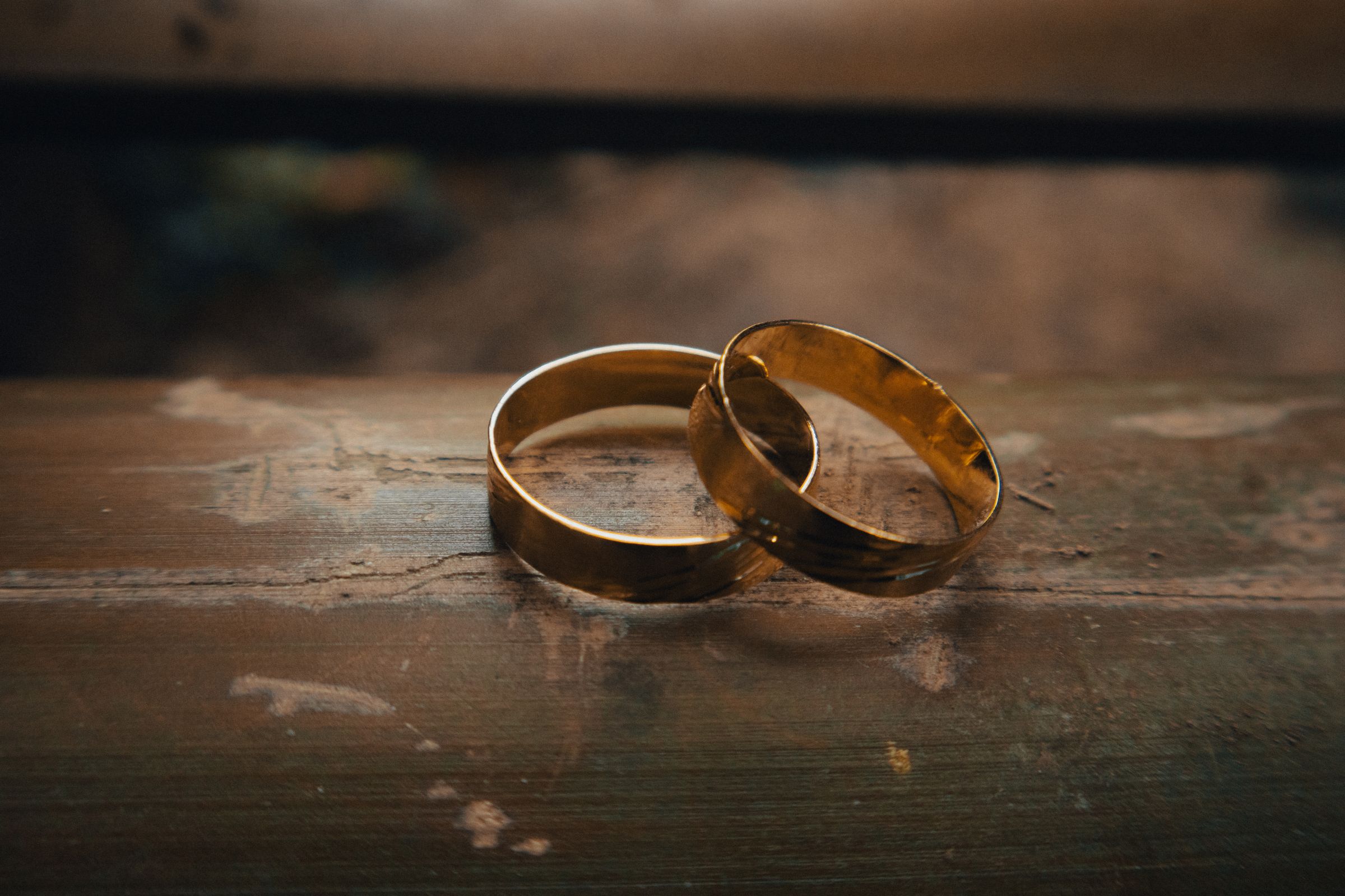 Two gold wedding rings on a rustic wooden surface