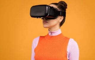 Woman enjoying virtual reality with VR headset against vibrant orange background.