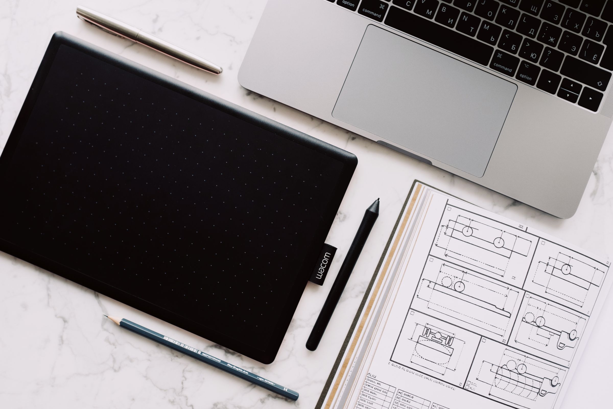 Desk with a laptop, drawing tablet and design sketches