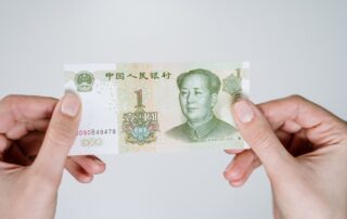 Close-up of hands holding a one Chinese Yuan note, showcasing currency details.