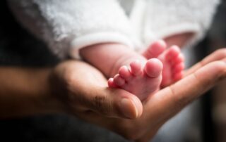 A close-up image of newborn baby feet resting in a gentle hand, showcasing innocence and new life.