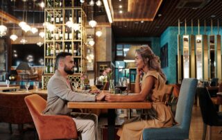 Couple enjoying a romantic dinner with wine in an elegant restaurant setting, creating a warm atmosphere.