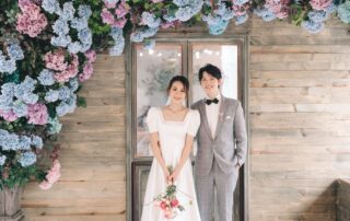 Beautiful bride and groom posing happily in front of floral backdrop, perfect for wedding inspiration.