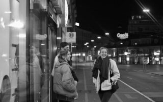 Black and white photo of friends laughing on a city street at night in Graz, Austria.