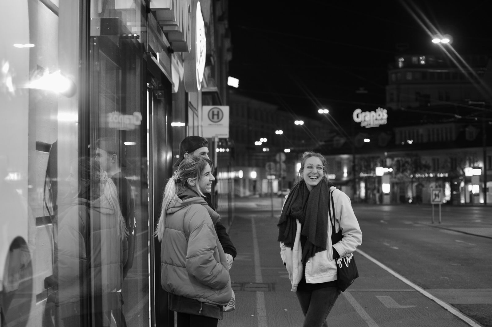 Black and white photo of friends laughing on a city street at night in Graz, Austria.