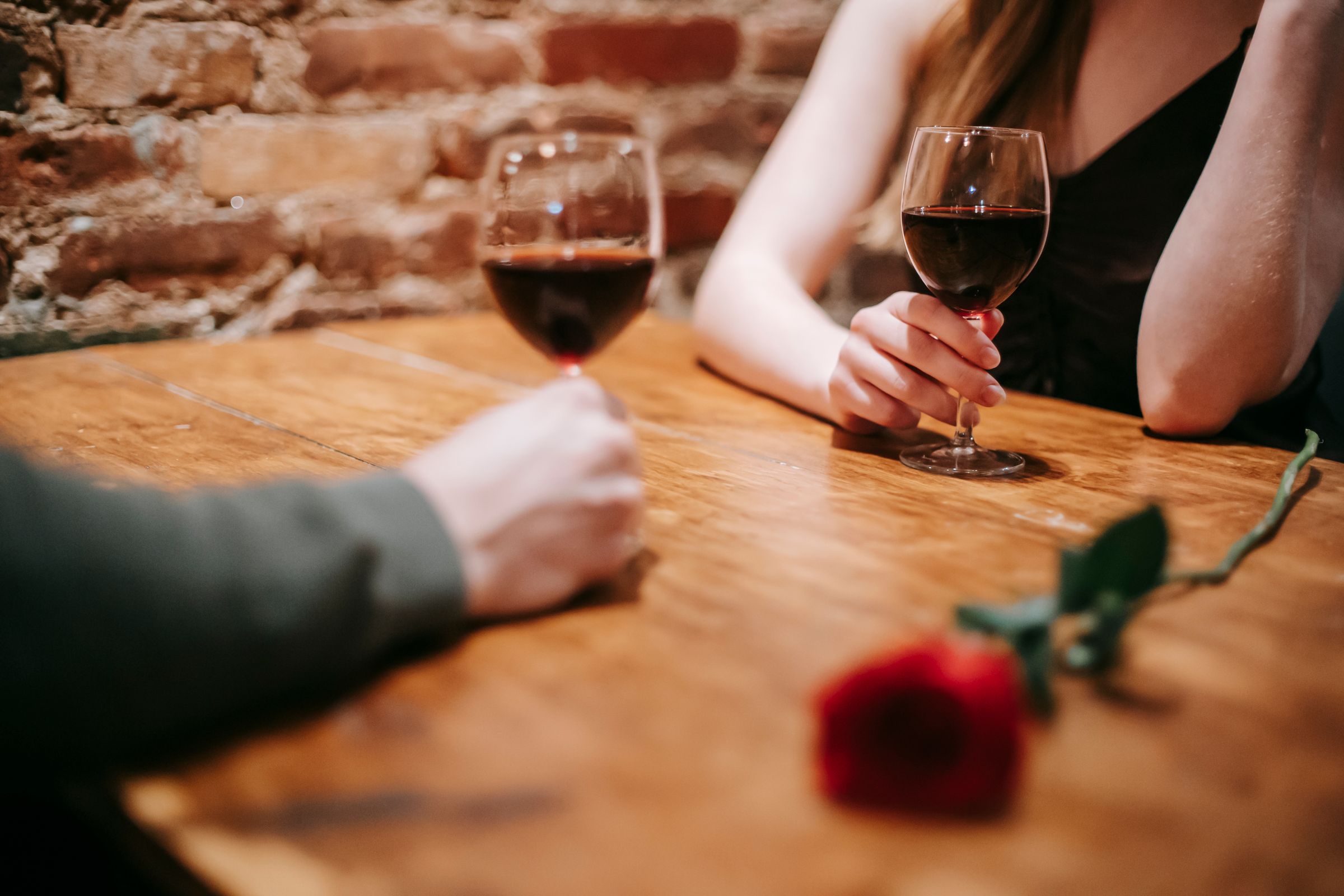 Elegantly dressed couple on a date with wine and a red rose