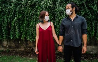 A couple wearing face masks holds hands, symbolizing love and protection during pandemic times.