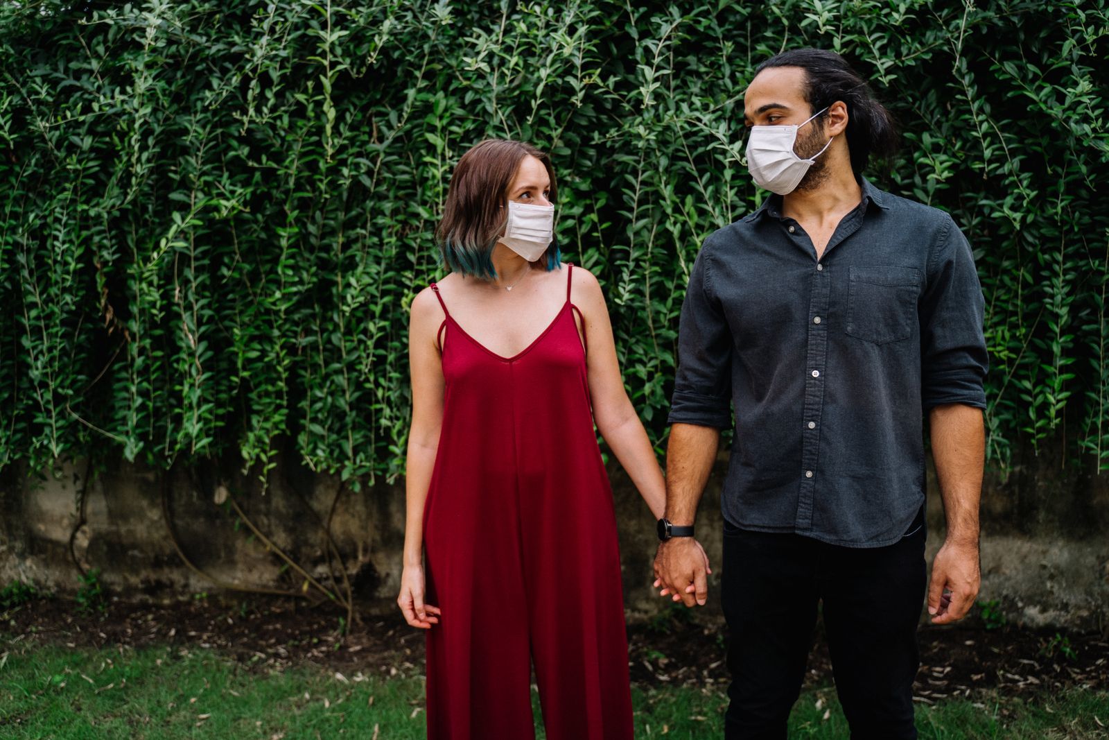 A couple wearing face masks holds hands, symbolizing love and protection during pandemic times.