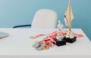 A collection of trophies and medals displayed on a white desk, symbolizing success and victory.