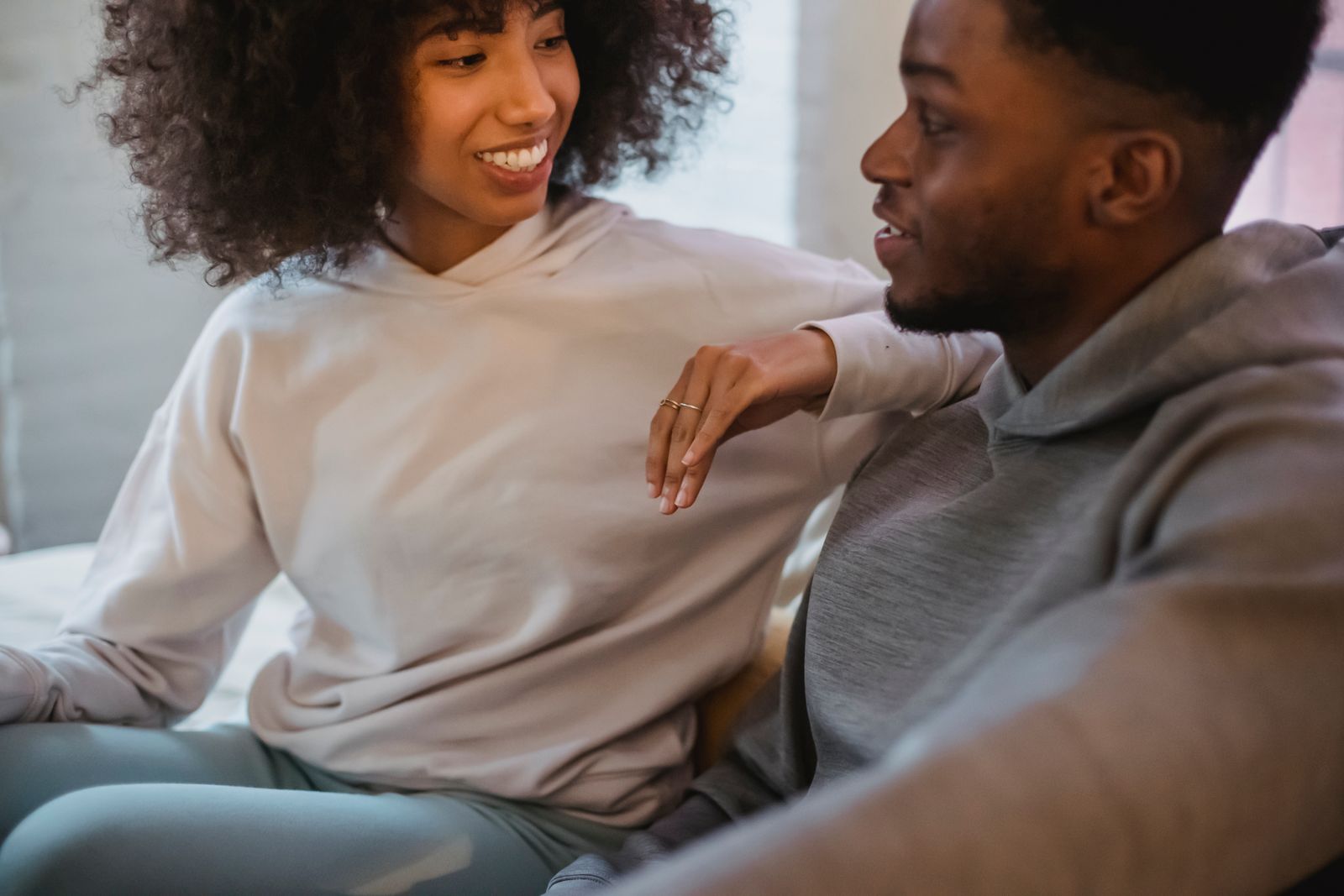 Crop positive African American female leaning on shoulder of black boyfriend while spending time together in light room